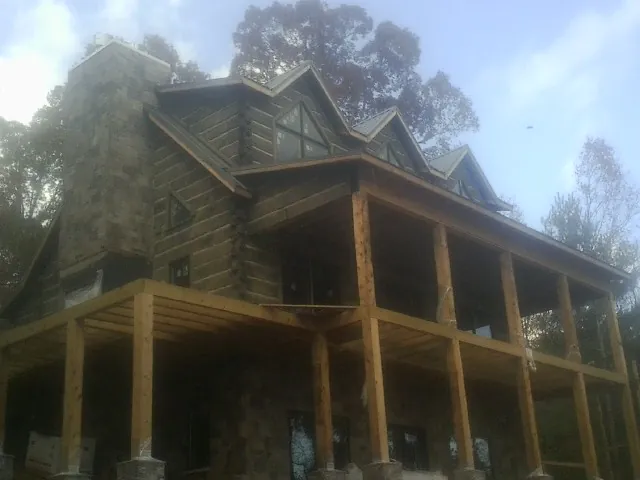Stone chimney and dormers on a large log home with a timber porch in Central City