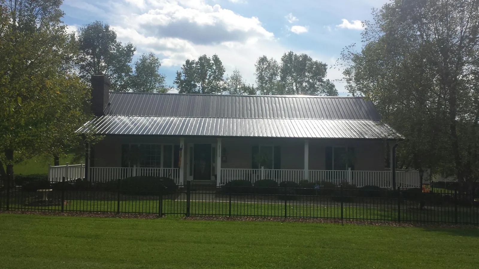 Gray metal roof on a brick ranch with a full width front porch — Gutter Guard Installation work by our crew in Central City